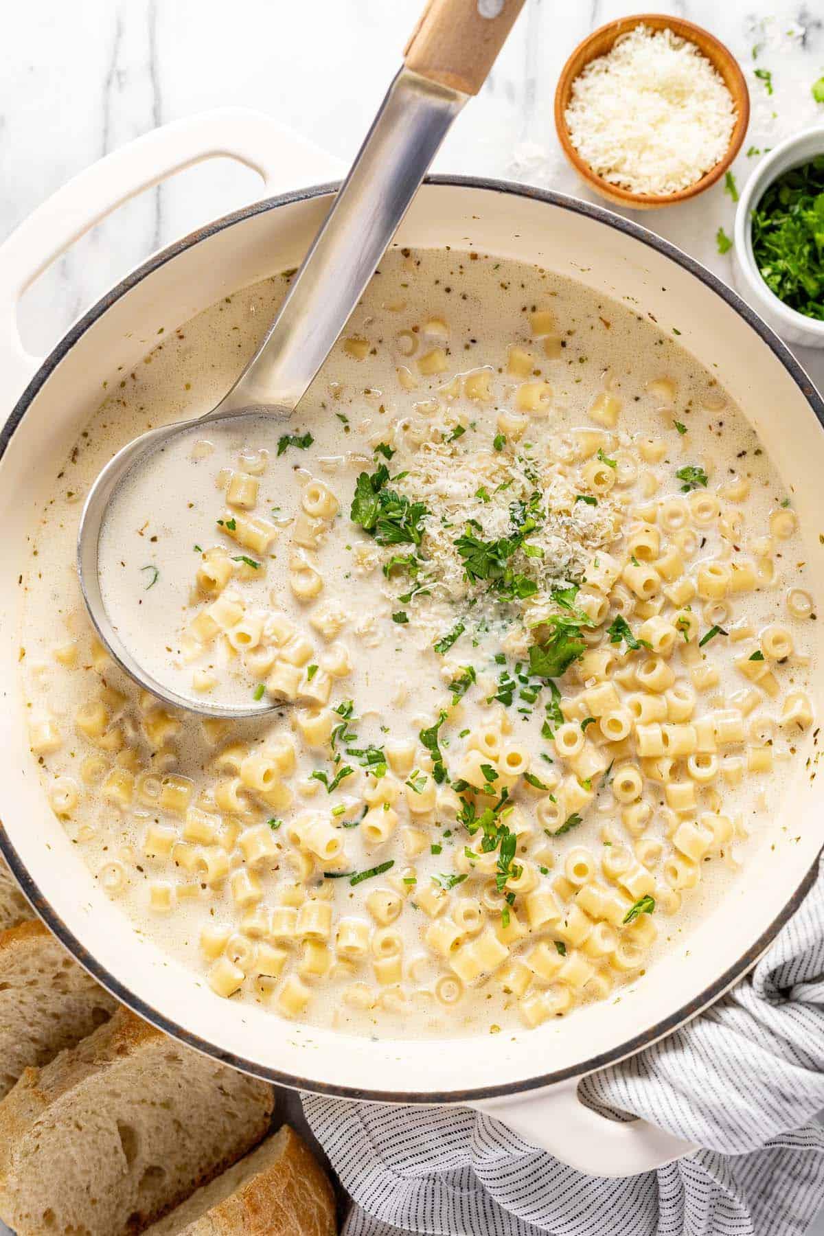creamy parmesan garlic soup in a white bowl with fresh parsley garnish