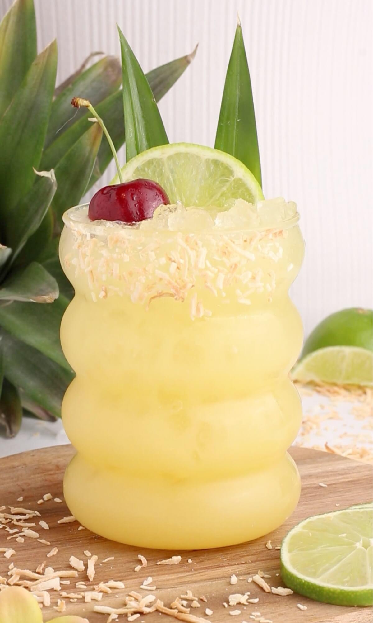 Close-up of a glass of non-alcoholic pineapple punch with ice and a garnish, vacation background