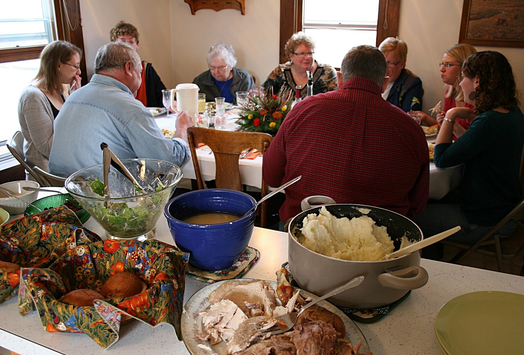 Vintage kitchen table with a family gathered, focus on a corn casserole
