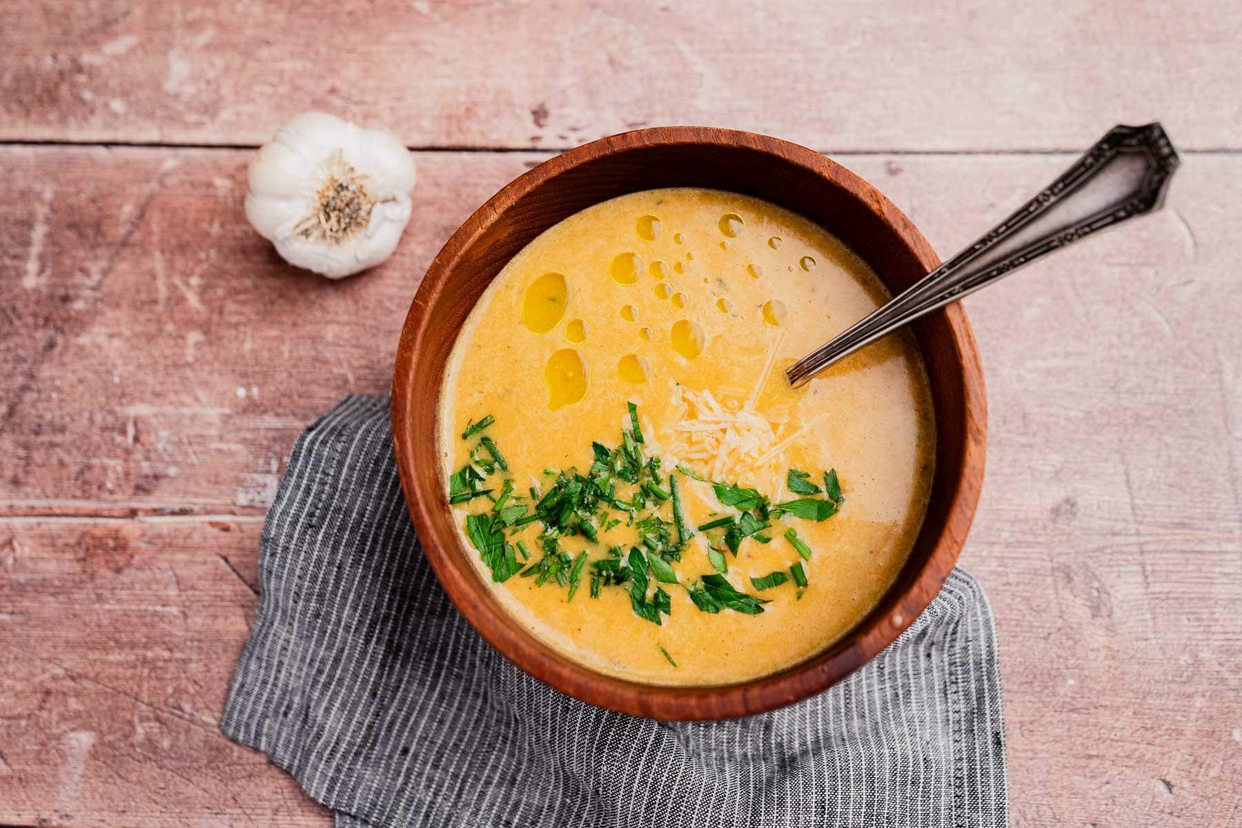 steaming bowl of creamy garlic soup, hands holding bowl, cozy