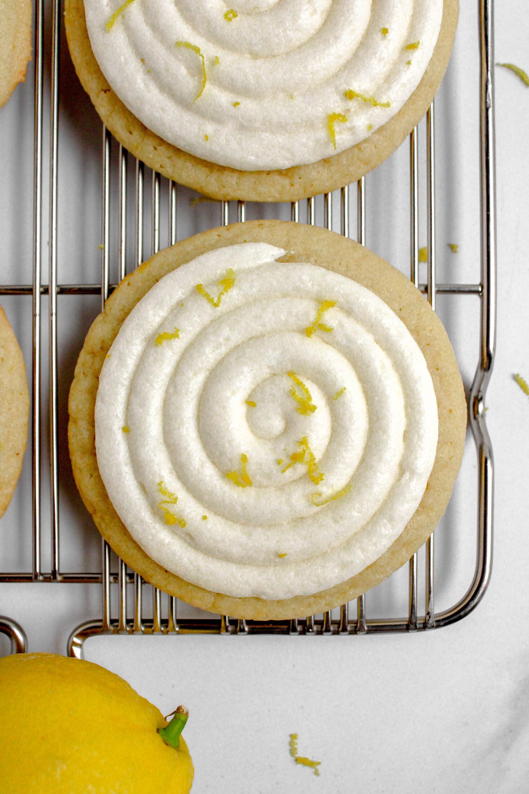 brightly lit studio shot of frosted lemon sugar cookies on a wire rack, with a lemon wedge and mint leaf garnish