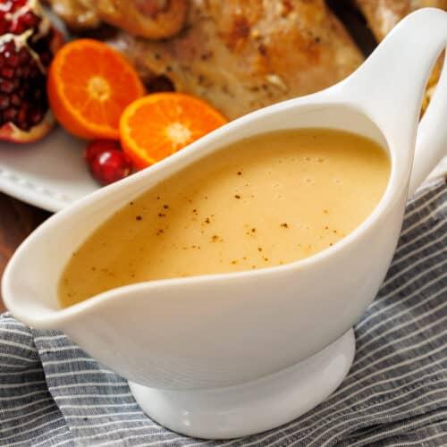 A close-up shot of rich, savory turkey gravy being poured into a gravy boat.