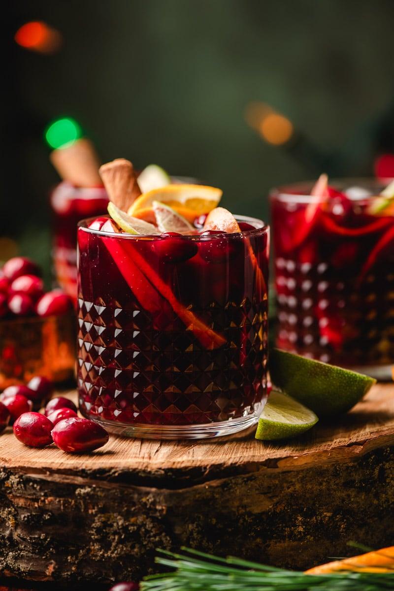ingredients for ruby sangria on a rustic wooden table with holiday fairy lights