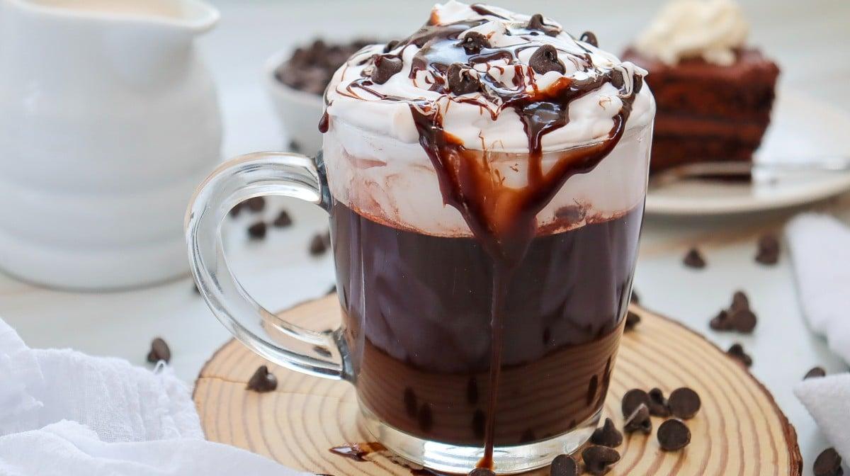 Mocha hot chocolate served in a fancy mug, topped with whipped cream, chocolate shavings, and a sprinkle of cocoa powder, styled for a blog.