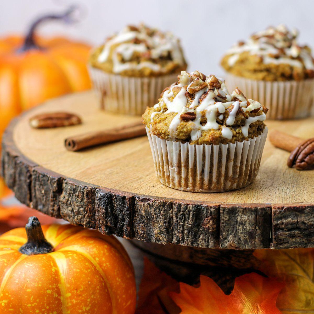 freshly baked pumpkin cinnamon muffins on a rustic wooden table with autumn leaves