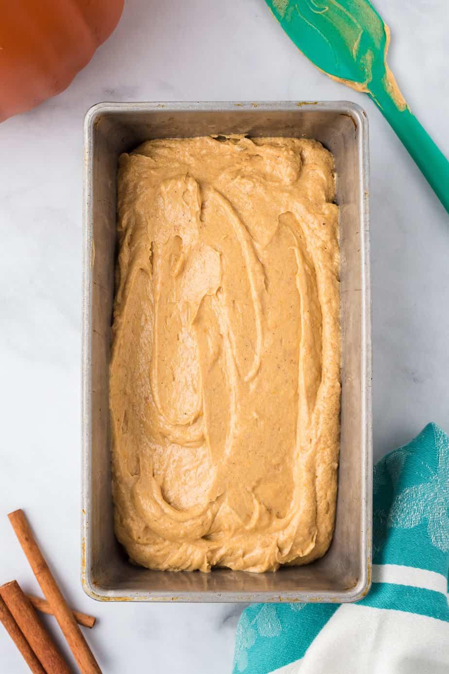 overhead shot of pumpkin bread batter being poured into a loaf pan