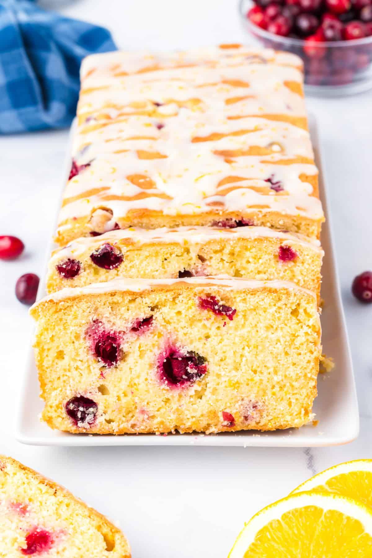 Slice of cranberry orange bread with glaze, showing tender crumb and cranberries