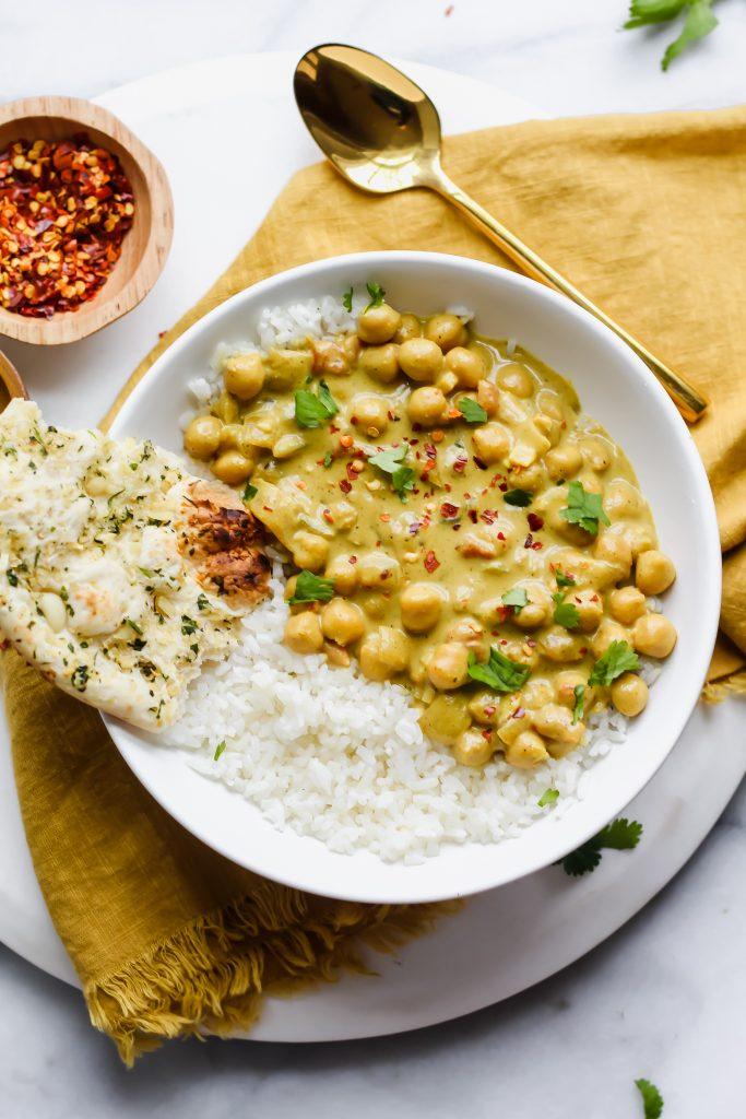 A person serving a bowl of chickpea curry