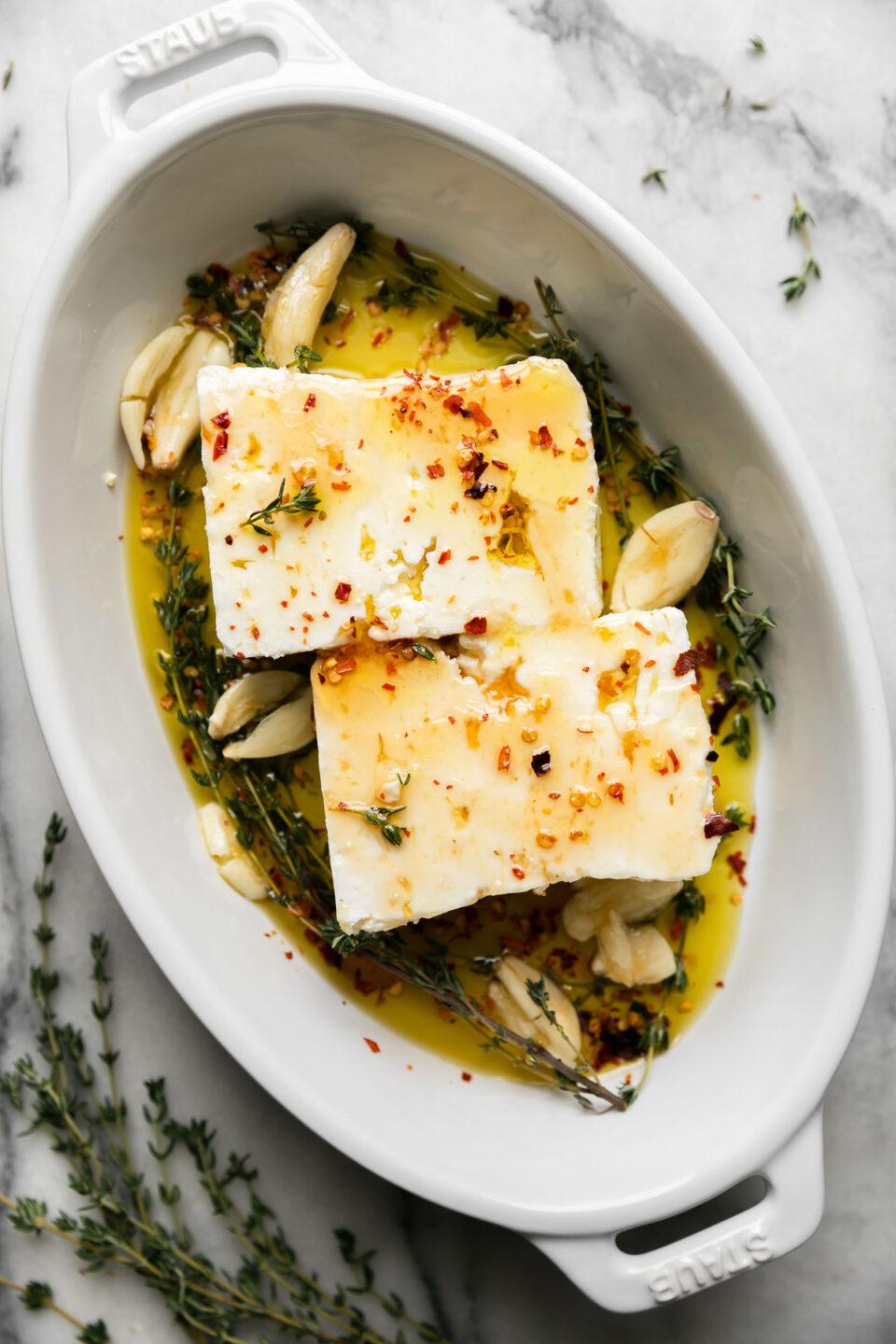 Block of feta cheese on a baking dish with olive oil, before baking