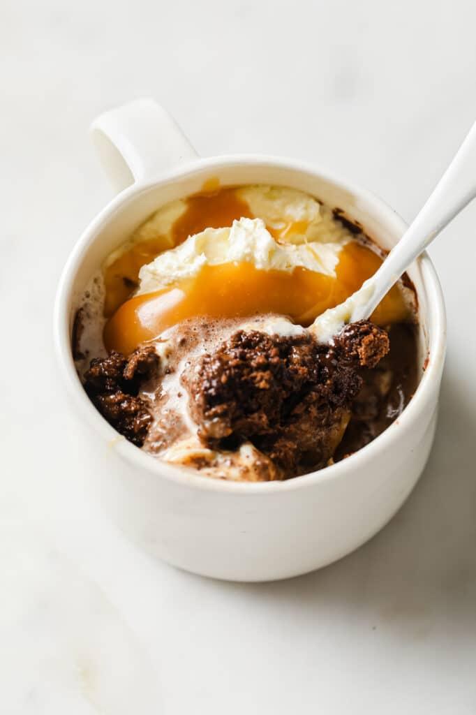 Overhead shot of a dark chocolate sea salt mug cake in a white mug with a spoon