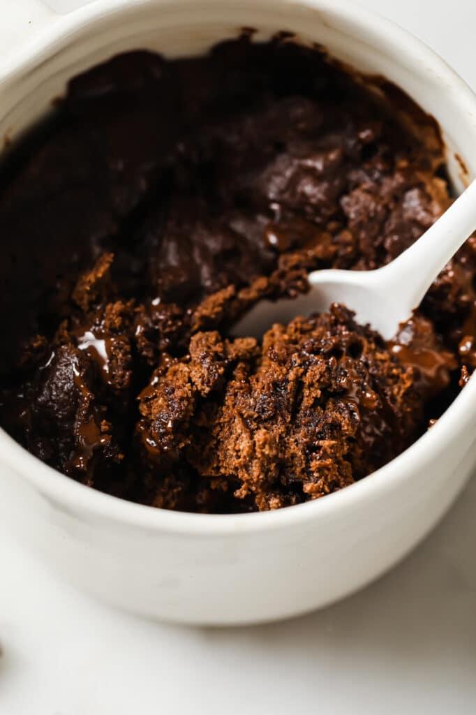 Close-up shot of a spoonful of dark chocolate sea salt mug cake being taken out of the mug