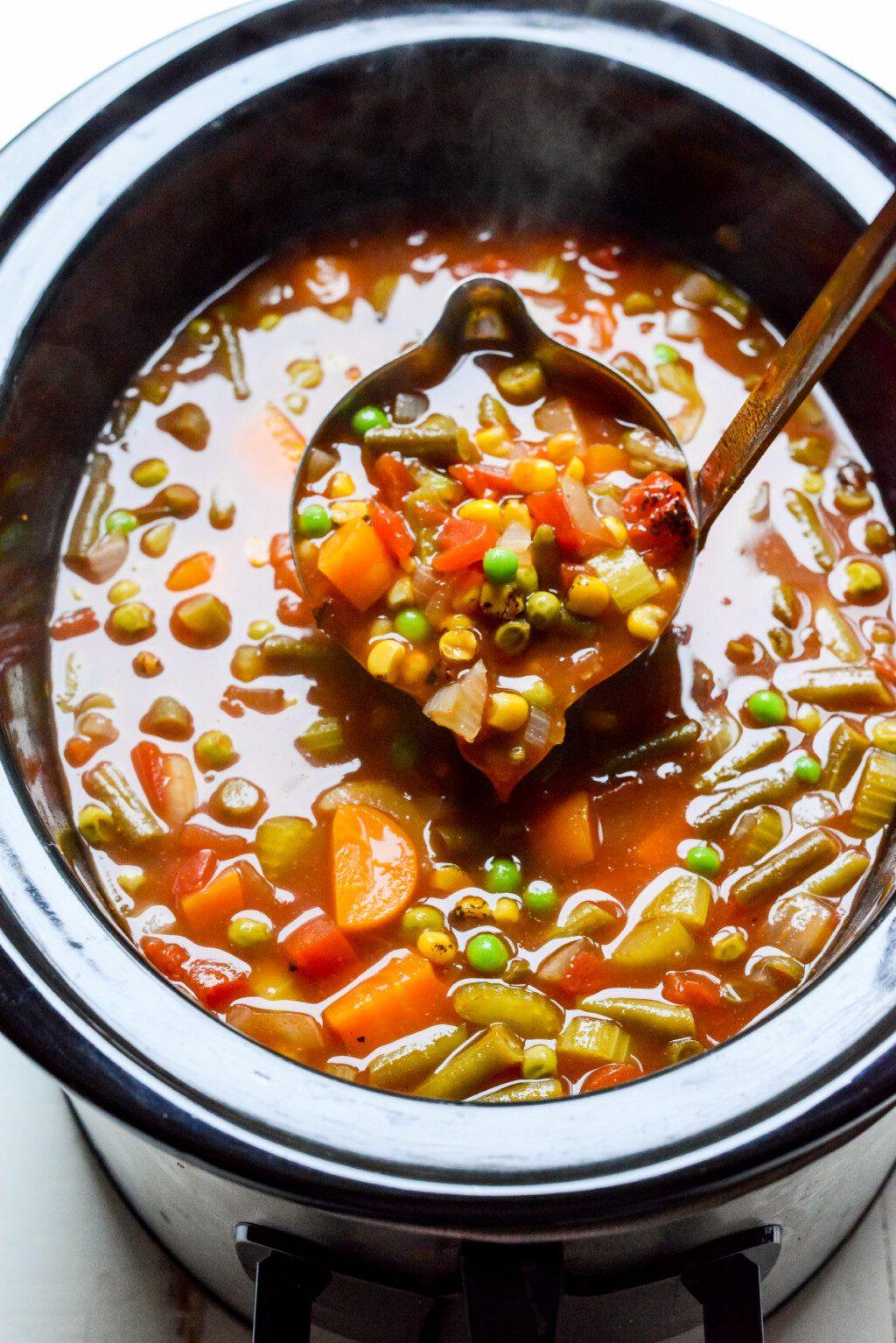 Slow cooker filled with simmering vegetables and broth