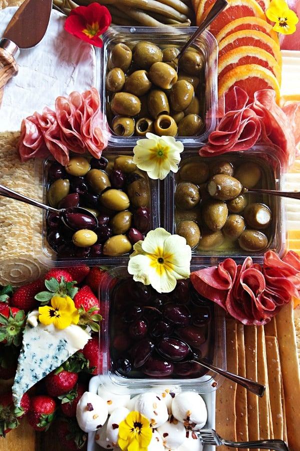 woman arranging olives on a charcuterie board