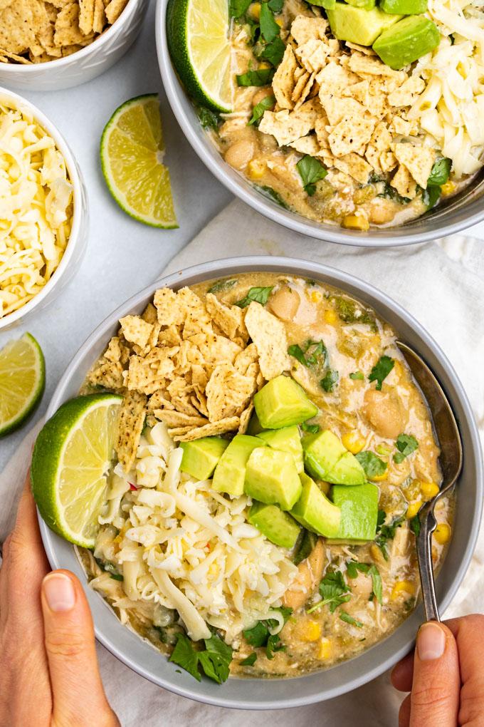 overhead shot of white chicken chili bowl with various toppings like avocado slices and tortilla strips