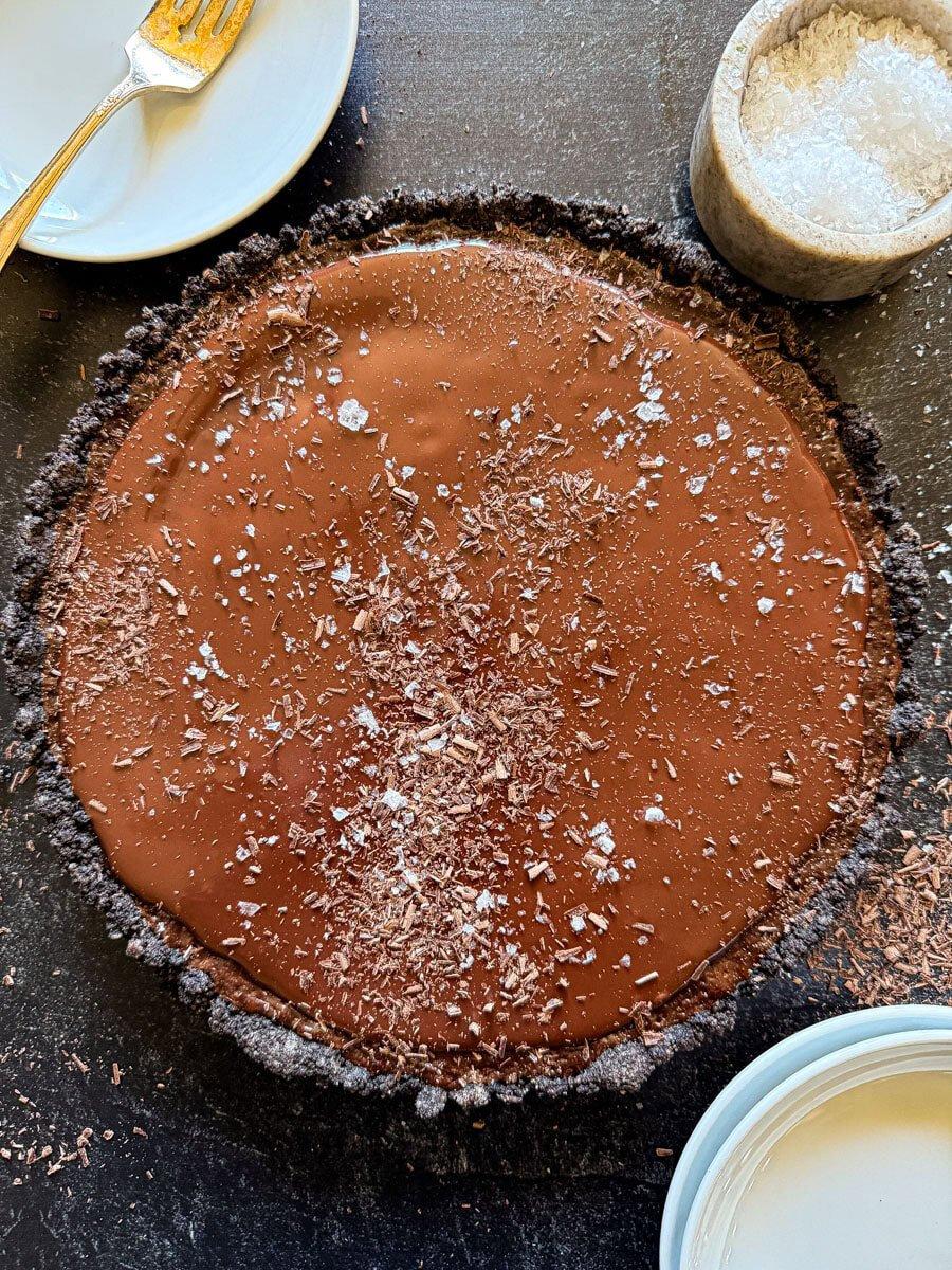close up of someone sprinkling sea salt on a slice of chocolate cake