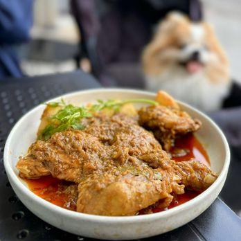 Amelia Hayes smiling in a kitchen, holding a plate of bright citrus chicken