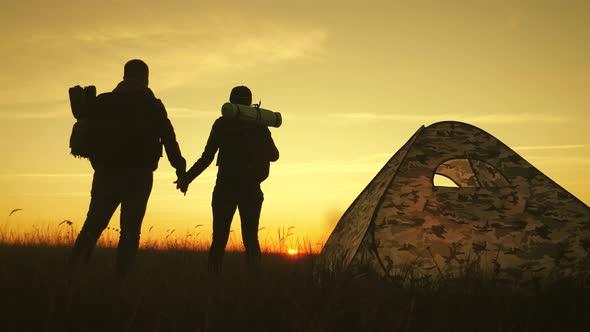 couple holding hands and watching the sunset from a campsite
