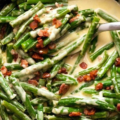 A close-up of Green Bean Parmesan Bake with a spoonful being lifted, showing creamy sauce and green beans