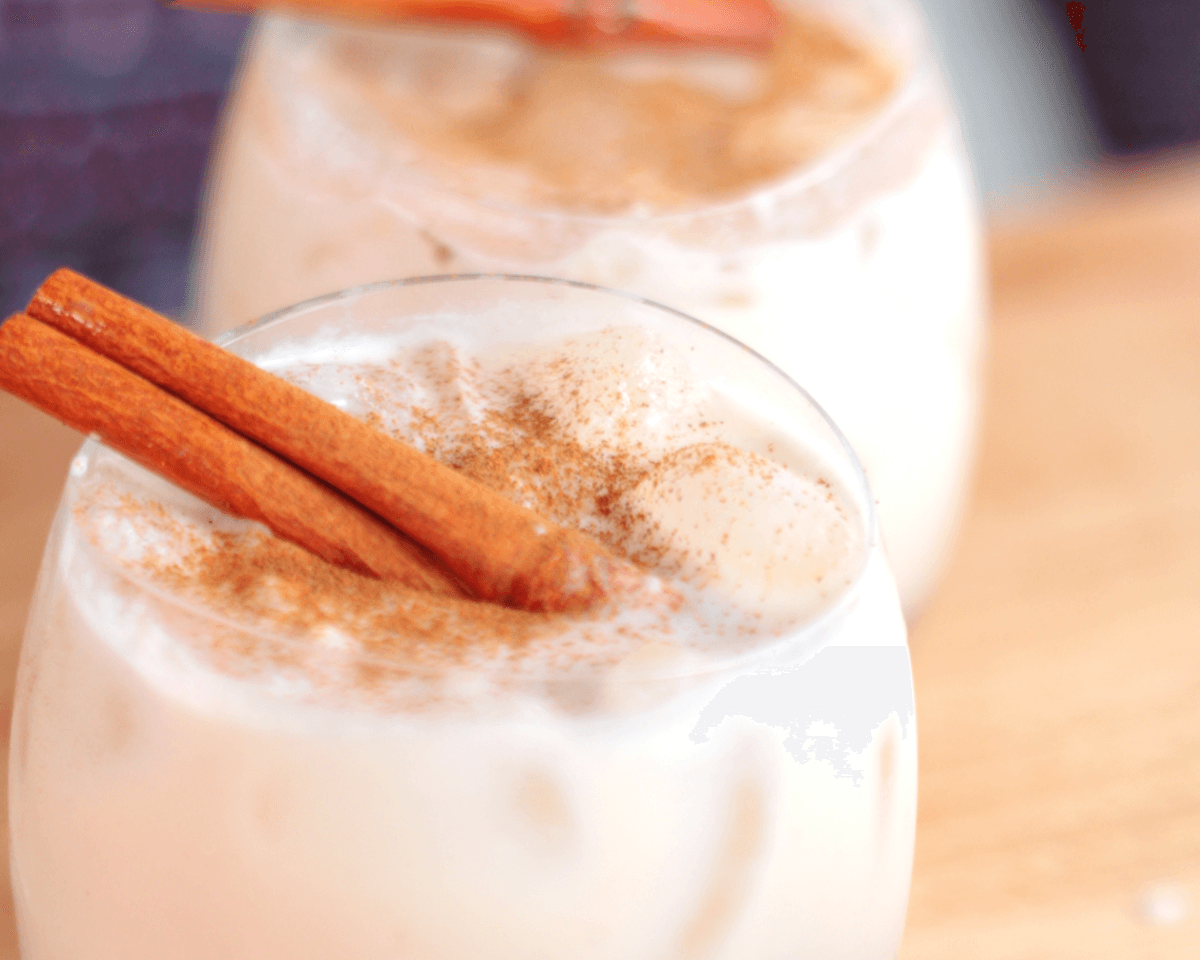 Extreme close-up of thick, creamy Coquito gently swirling in a clear glass, highlighting its smooth texture