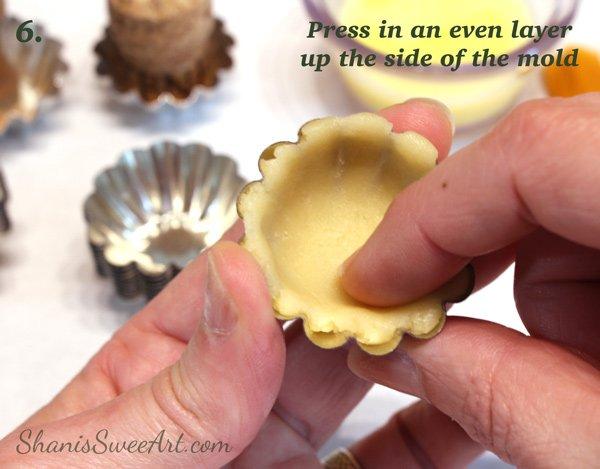 hands pressing pastry dough into mini tartlet molds