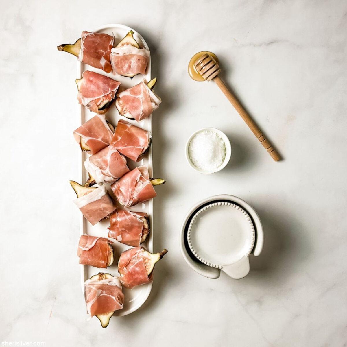 Close-up of prosciutto slices draped artfully on a charcuterie board with fresh figs