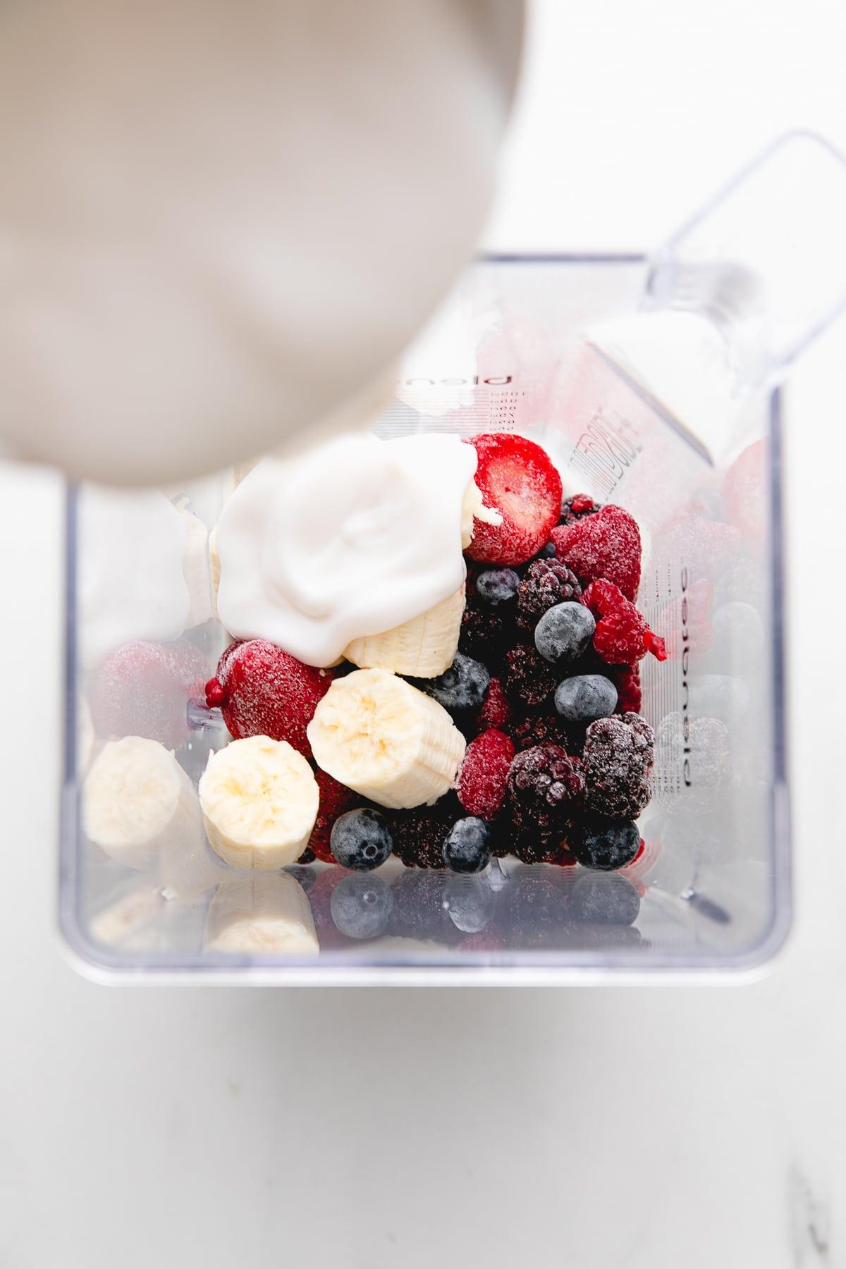 close-up shot of a blender filled with berries and yogurt, ready to be blended