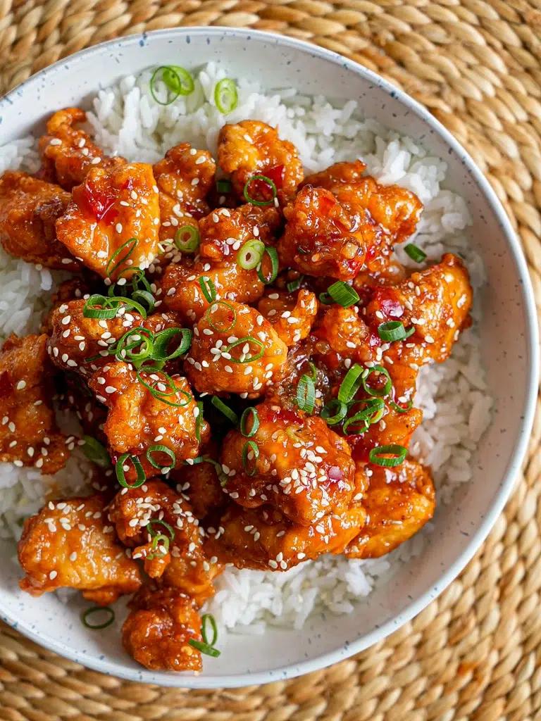 Close-up of crispy fried chicken pieces glistening with sweet chili sauce