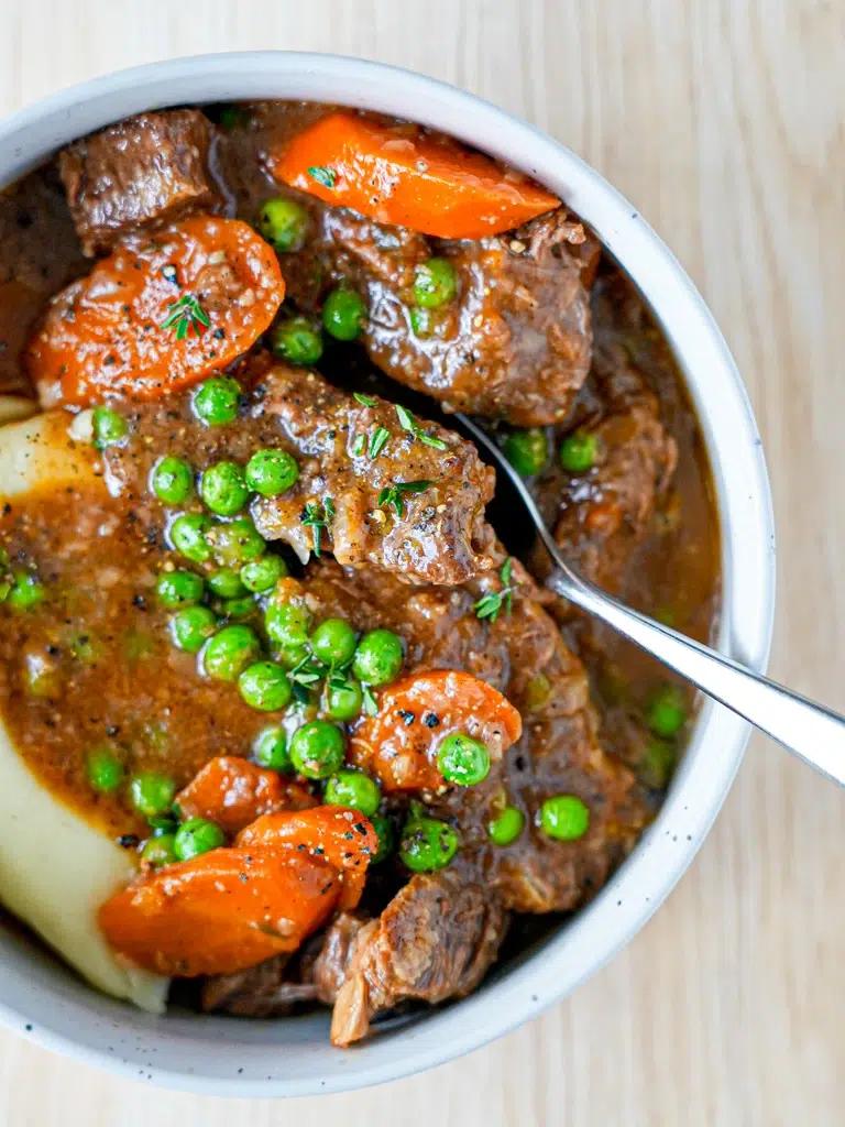 Close-up of tender, slow-cooked beef stew pieces with rich gravy and vegetables