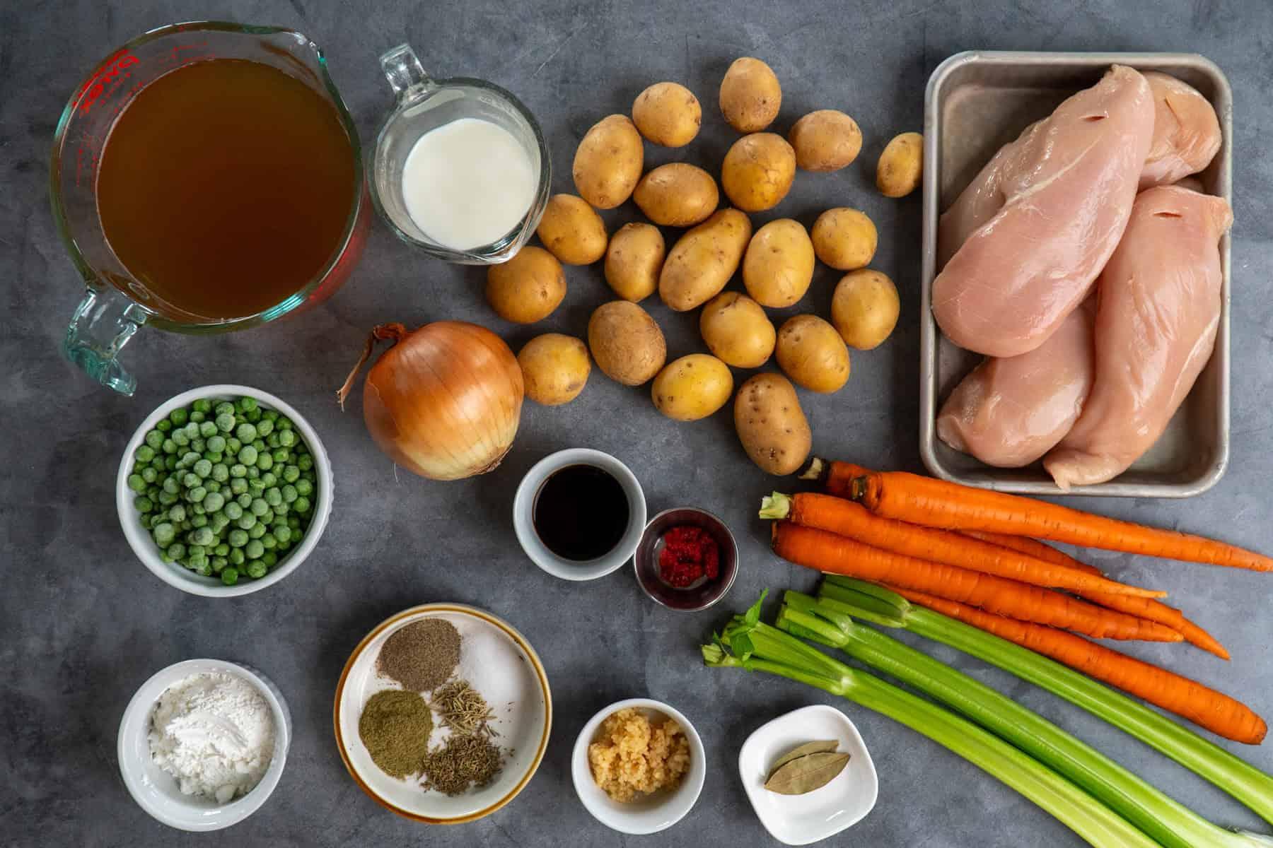 ingredients for slow cooker chicken stew laid out on a wooden table