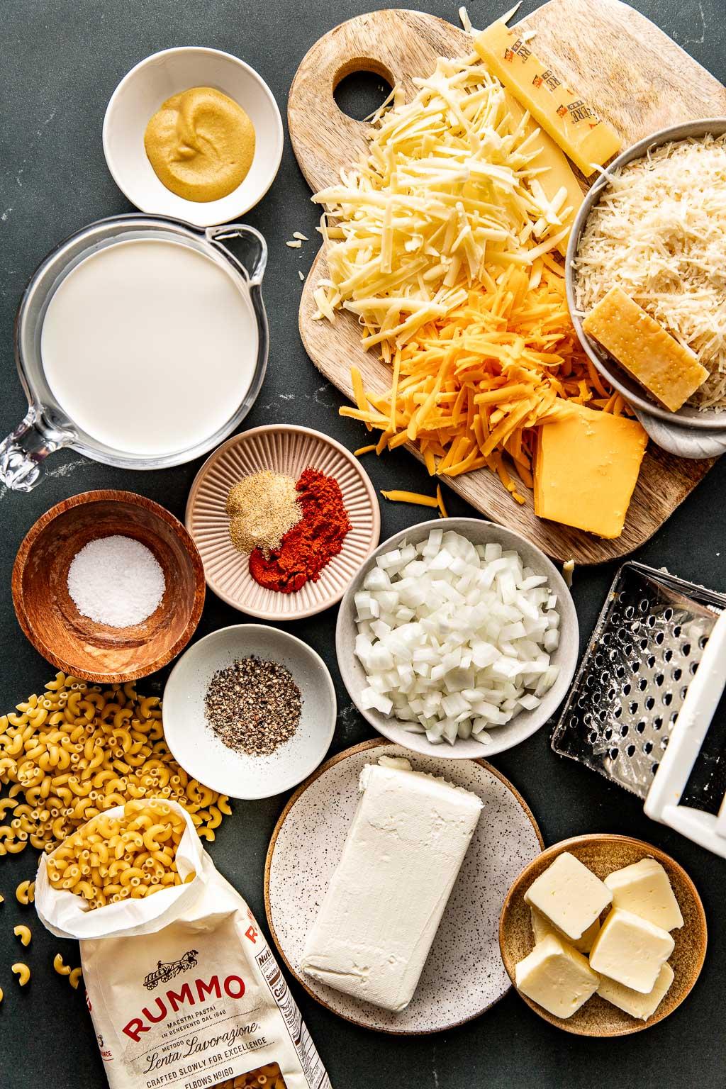 Ingredients for mac and cheese laid out on a wooden table, including pasta, milk, cheese