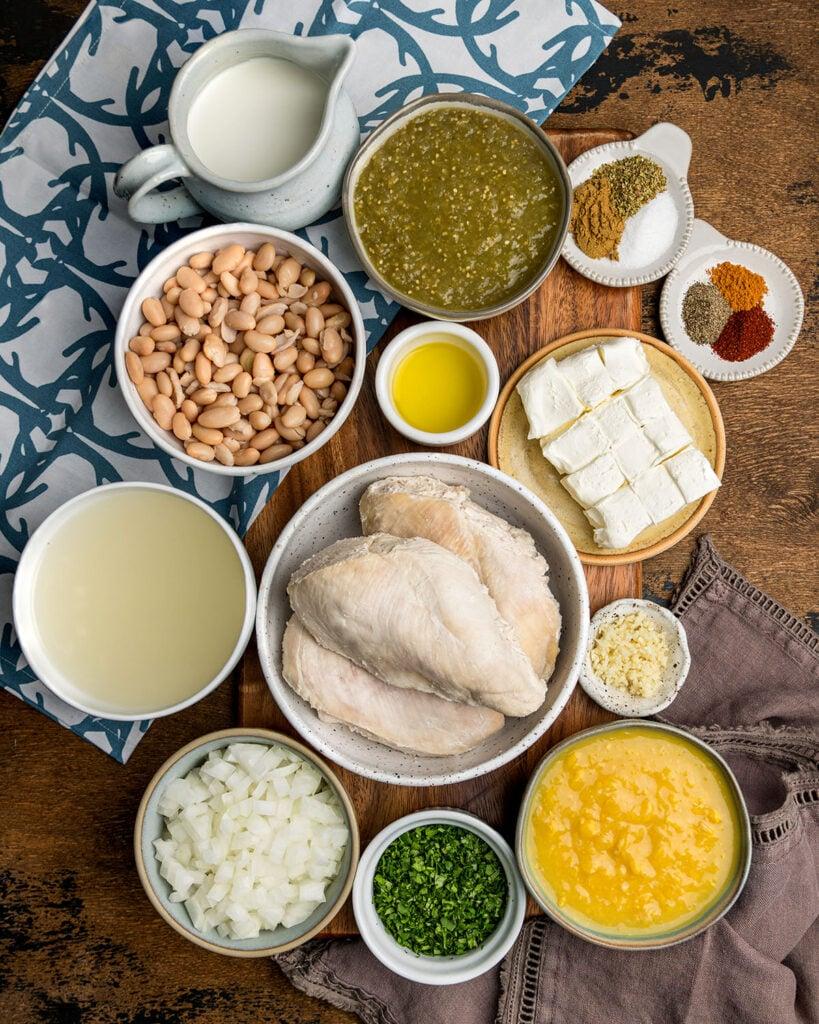 ingredients for cream cheese white chicken chili laid out on a wooden countertop
