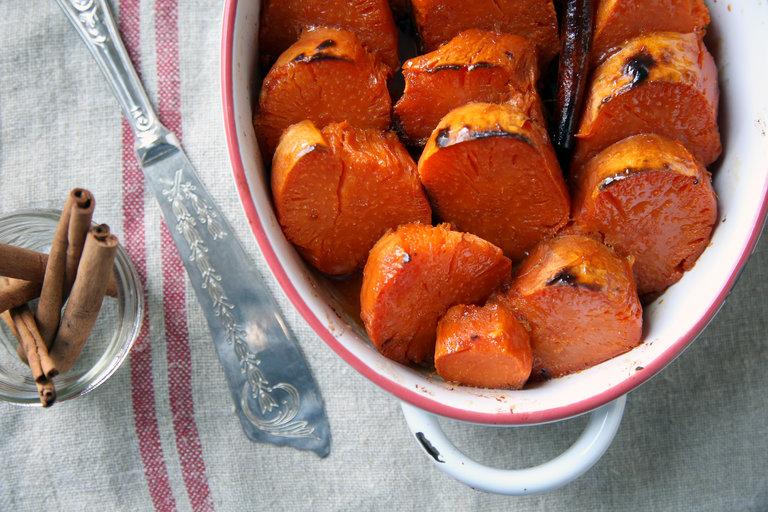 Ingredient shot of pure maple syrup, brown sugar, and cinnamon next to sweet potatoes