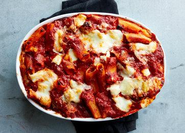 Ingredients for baked ziti, including pasta, cheese, and tomato sauce, neatly laid out on a kitchen counter