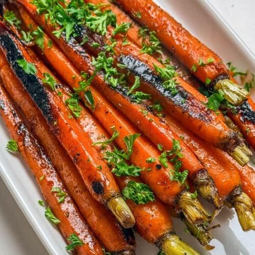 Close-up of golden honey glaze being poured over cooked carrots in a skillet