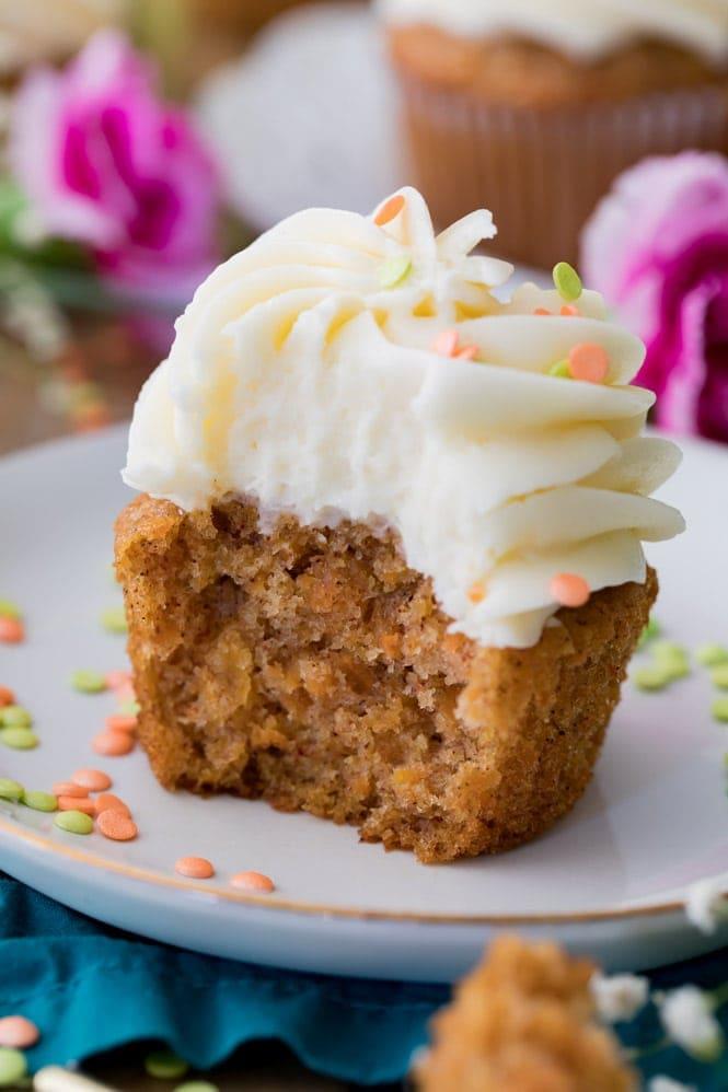 close up shot of carrot cake mini cupcakes with cream cheese frosting and candied carrots
