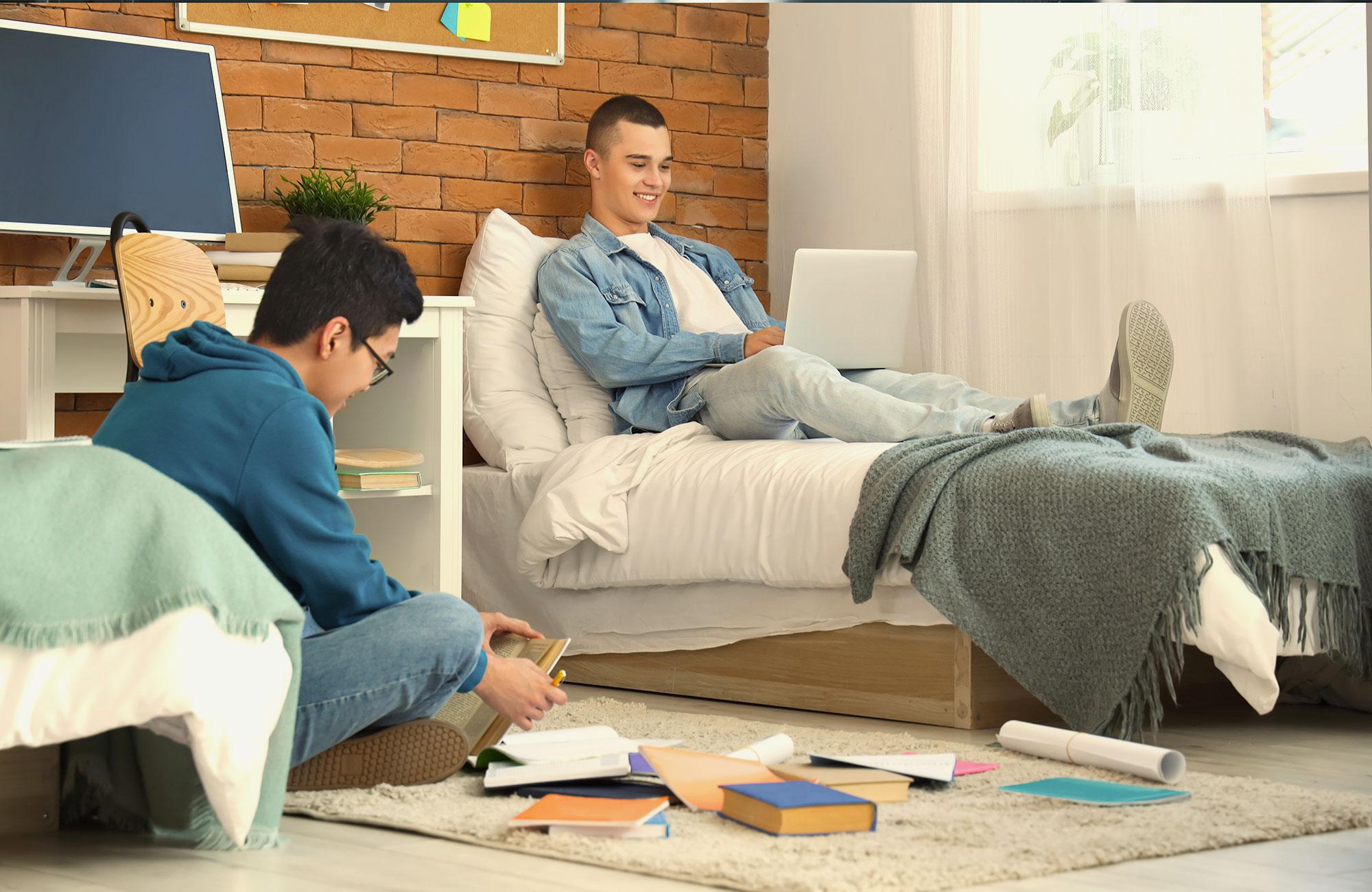 Happy and relaxed student studying in a comfortable dorm room