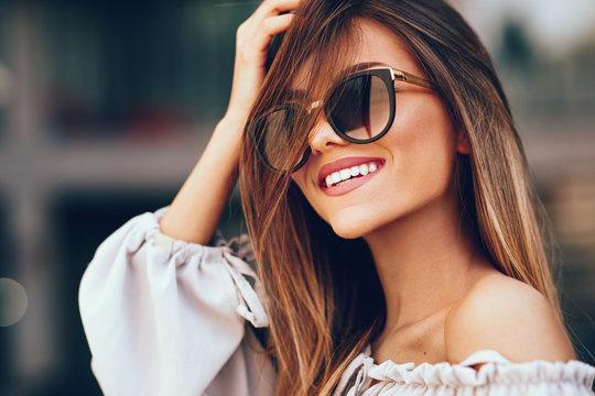 woman smiling while wearing stylish sunglasses