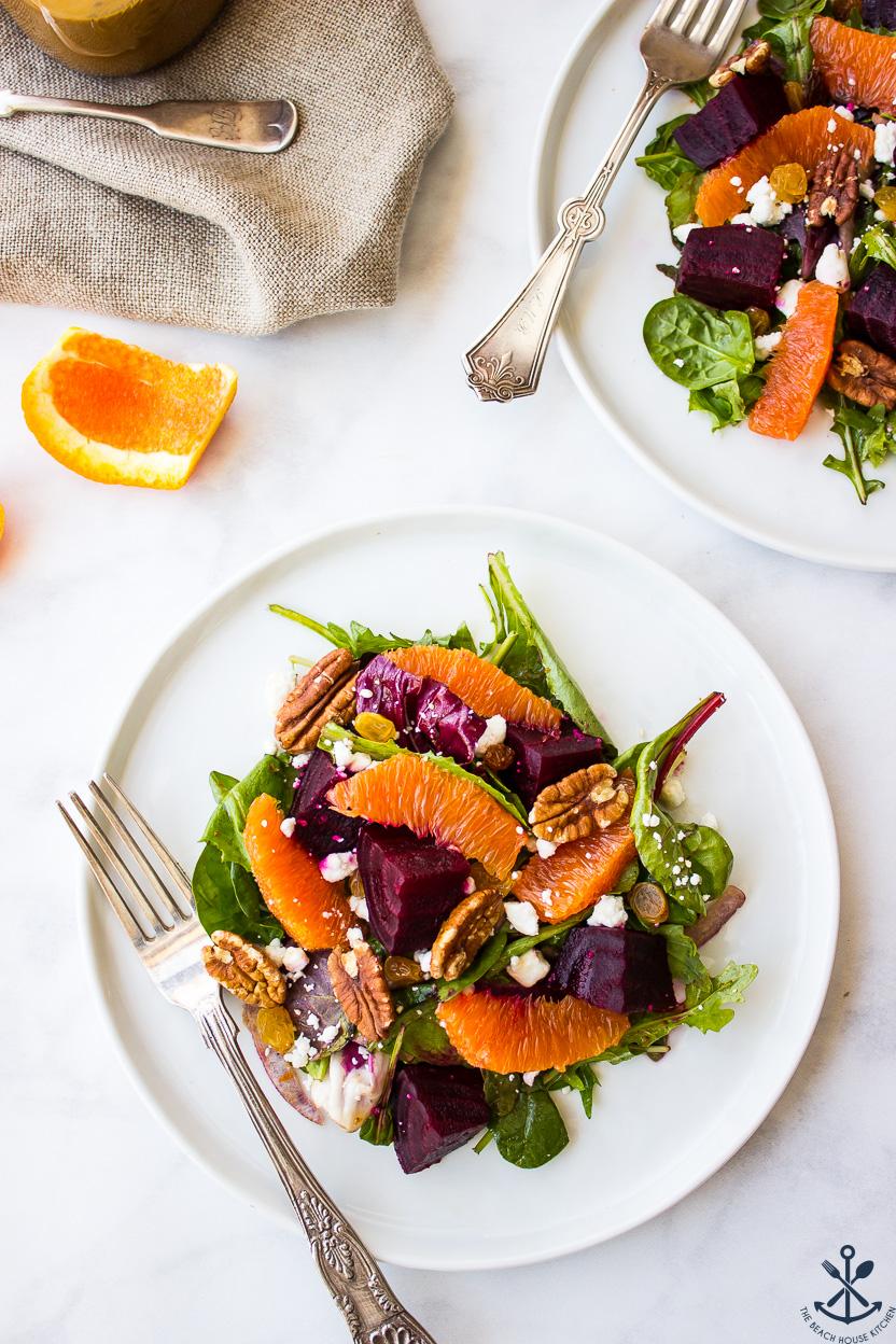 Overhead shot of a colorful beet and citrus salad on a white plate with fork