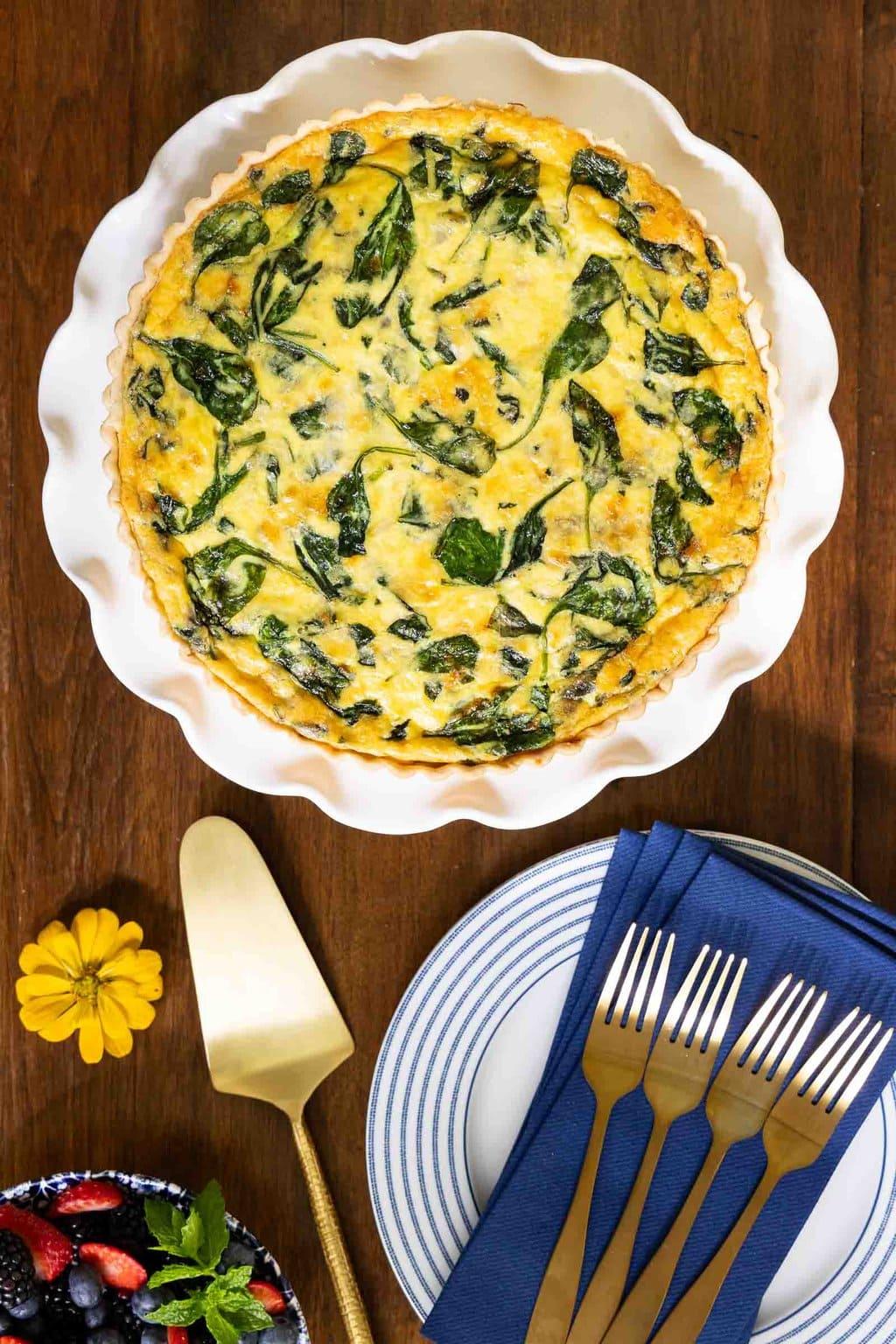overhead shot of a slice of egg and spinach quiche being lifted from the pie dish