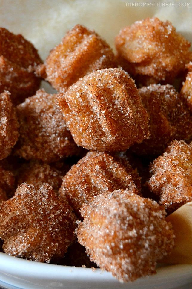 A close-up of someone taking a bite of a mini churro ice cream bowl