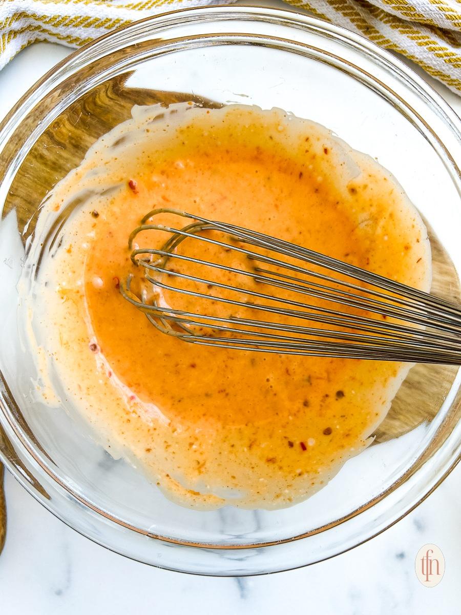 Homemade Bang Bang sauce being whisked in a small bowl, creamy texture
