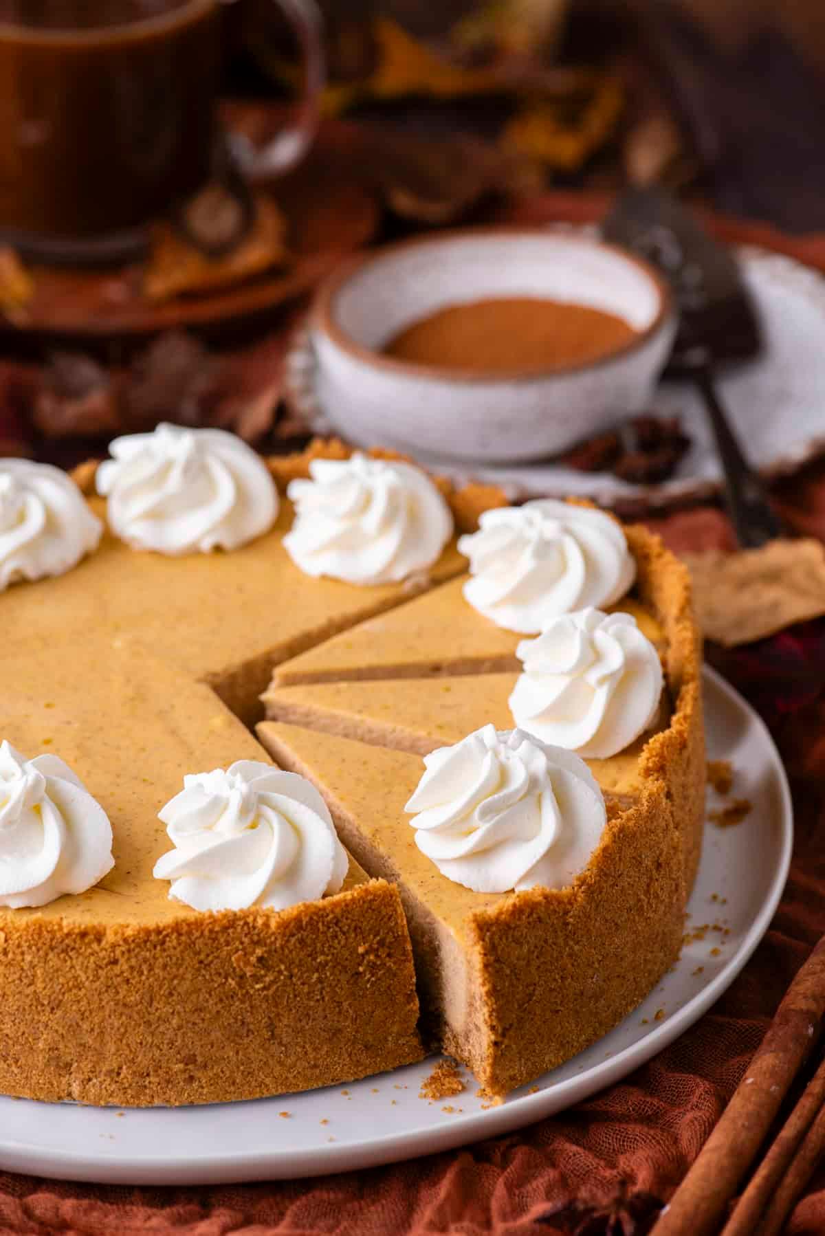 Pumpkin cheesecake being gently removed from a springform pan, showing its perfect golden crust
