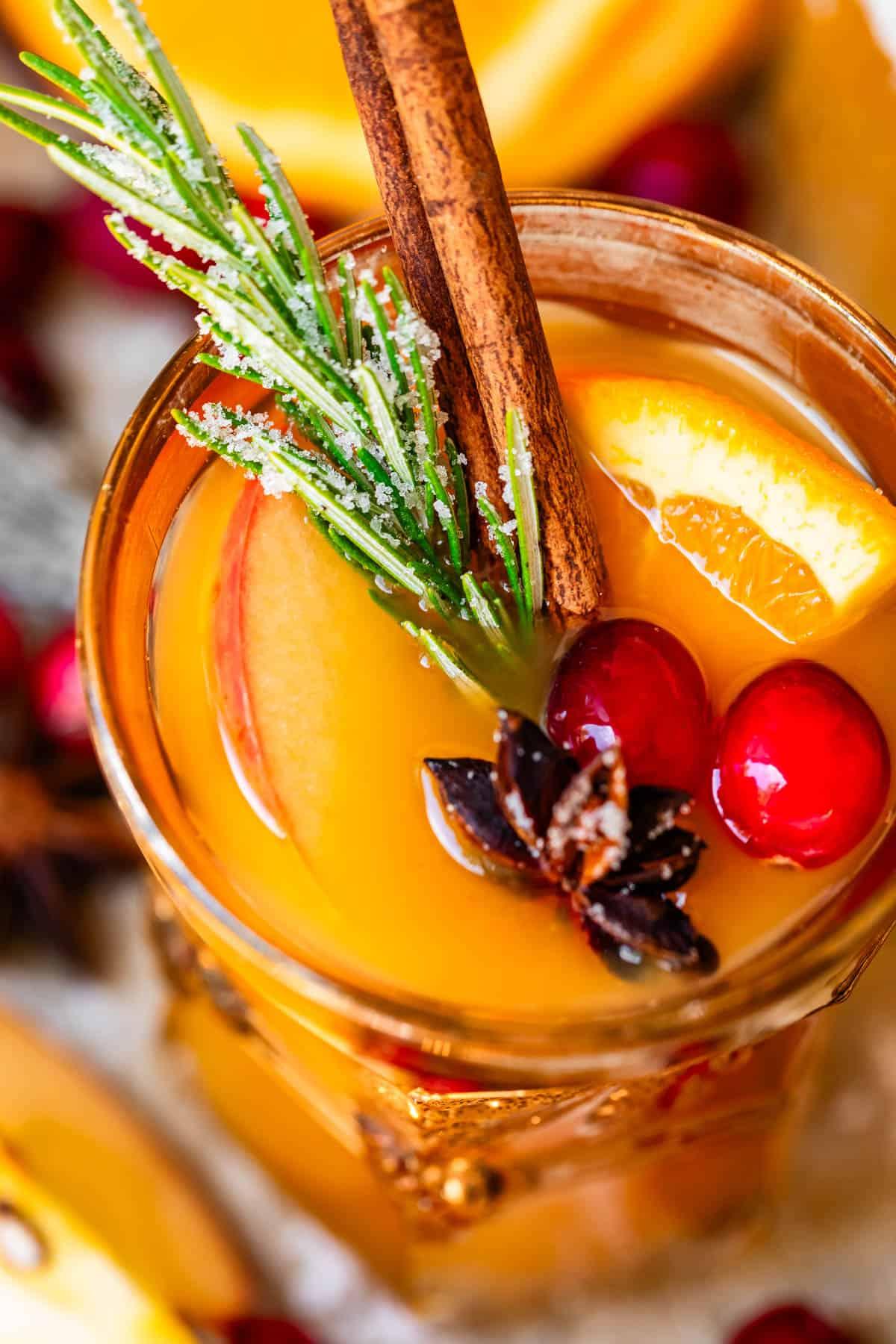 A person warmly greeting friends at a Friendsgiving party, holding a glass of spiced apple cider