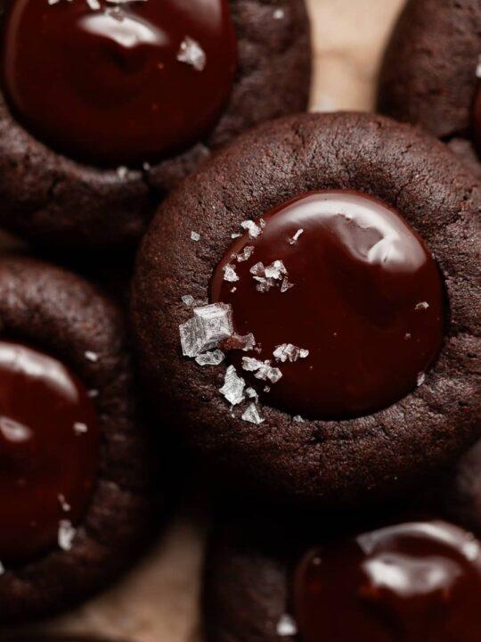 Platter of chocolate thumbprint cookies with ganache, garnished with a sprinkle of sea salt