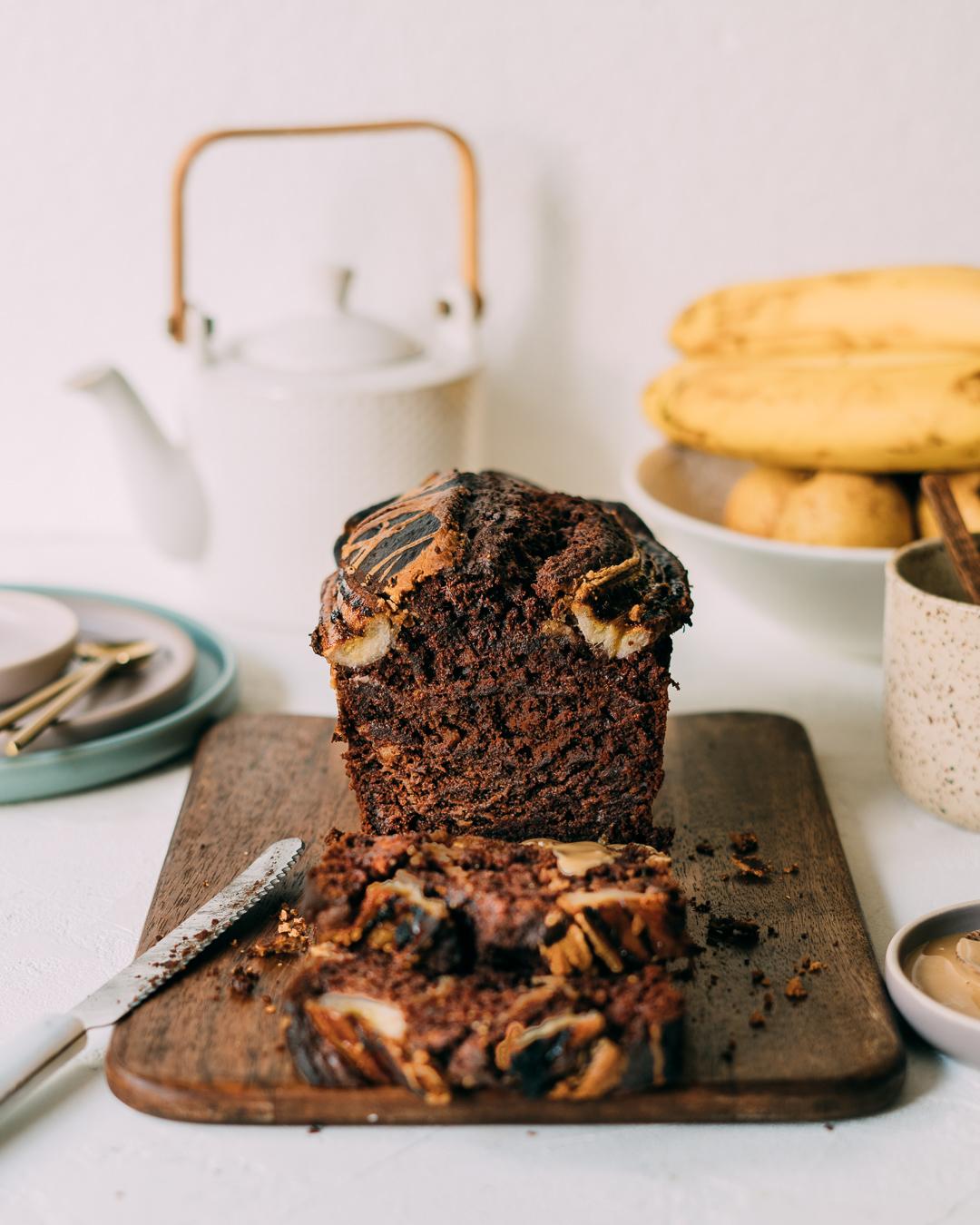 sliced banana bread with dark chocolate swirls on a cooling rack, rustic kitchen background