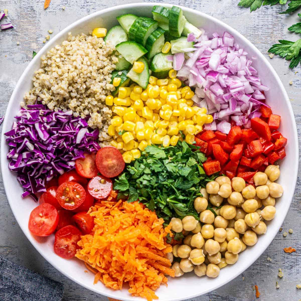 Variety of fresh, colorful vegetables chopped and ready for a quinoa bowl, with a bowl of cooked quinoa in the background