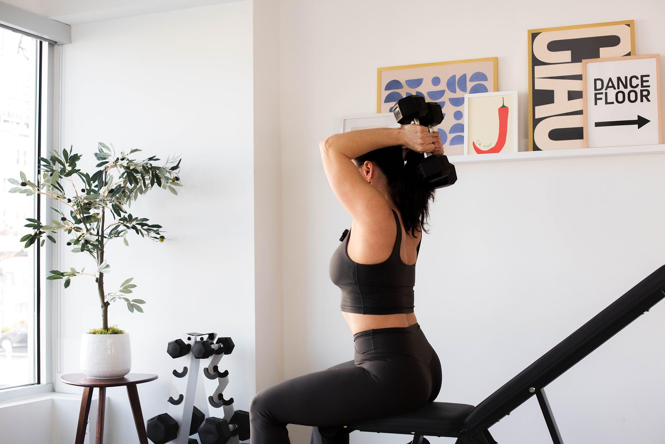 woman confidently lifting weights in a small home gym