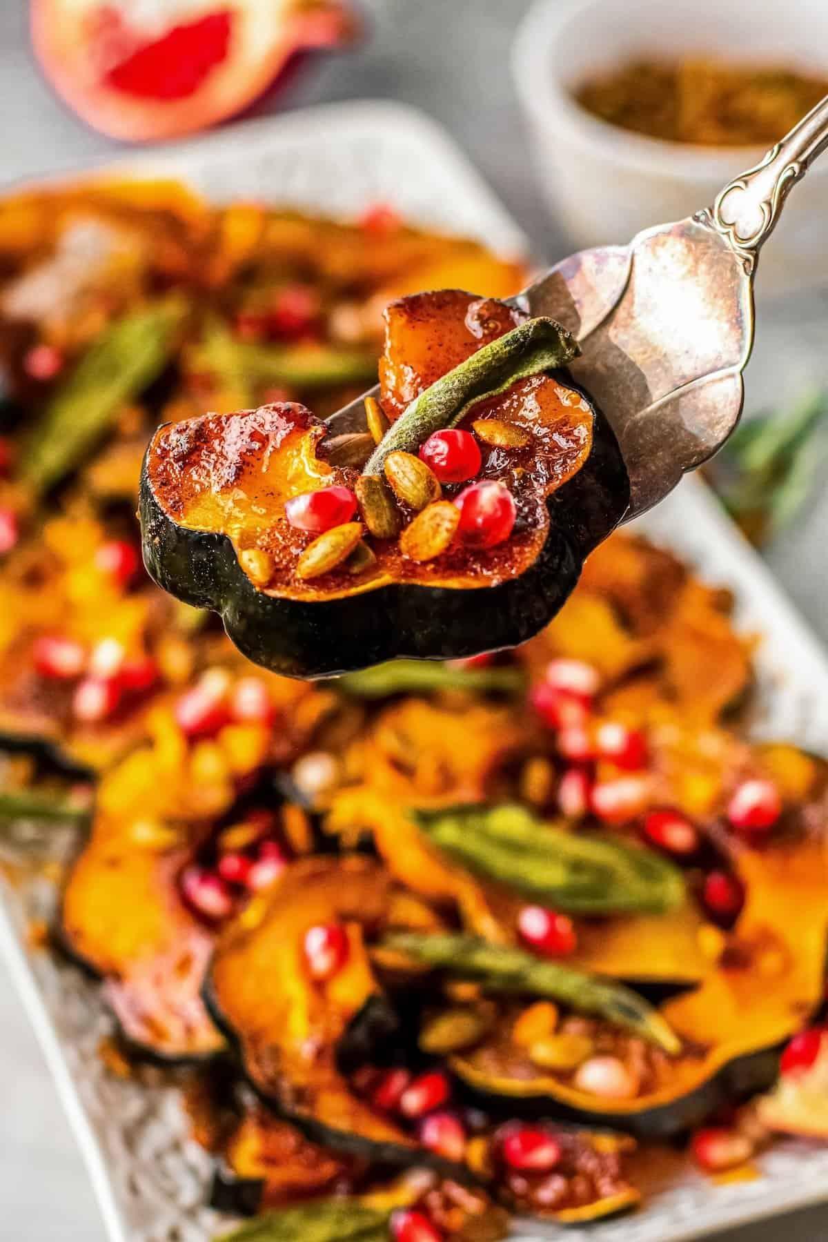 close-up of vibrant orange roasted pumpkin chunks with sage leaves on a baking sheet