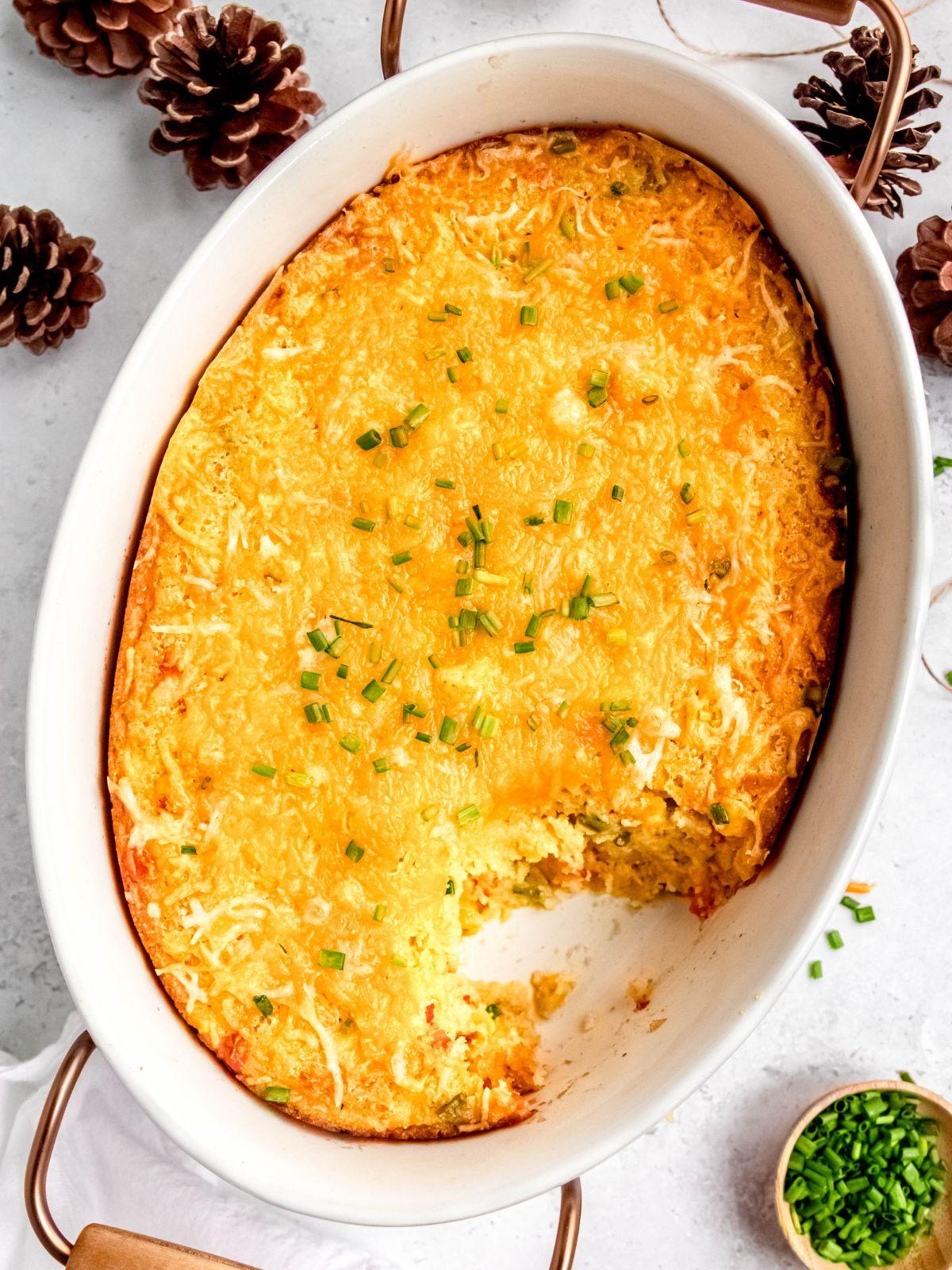 Overhead shot of a full corn casserole dish with crispy golden edges, cooling on a wire rack on a wooden table