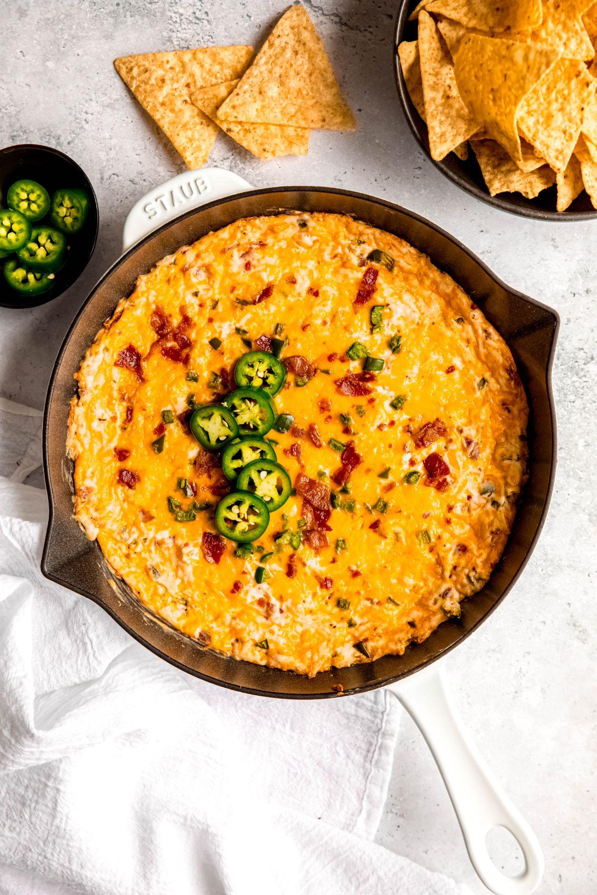 Gooey, cheesy jalapeño popper dip in a baking dish with tortilla chips